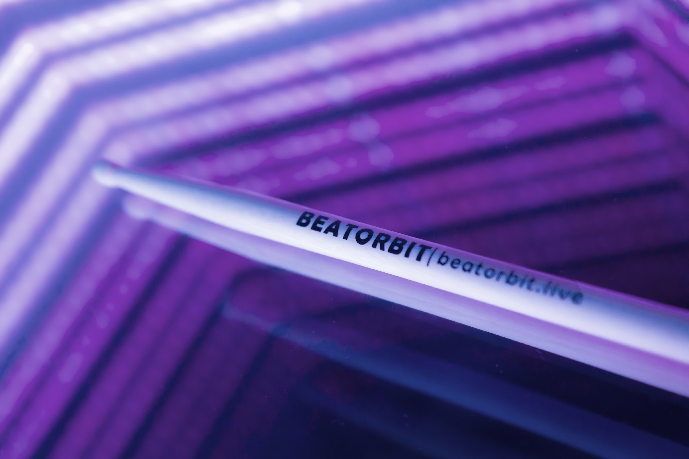 BeatOrbit branded drumstick over an illuminated drum